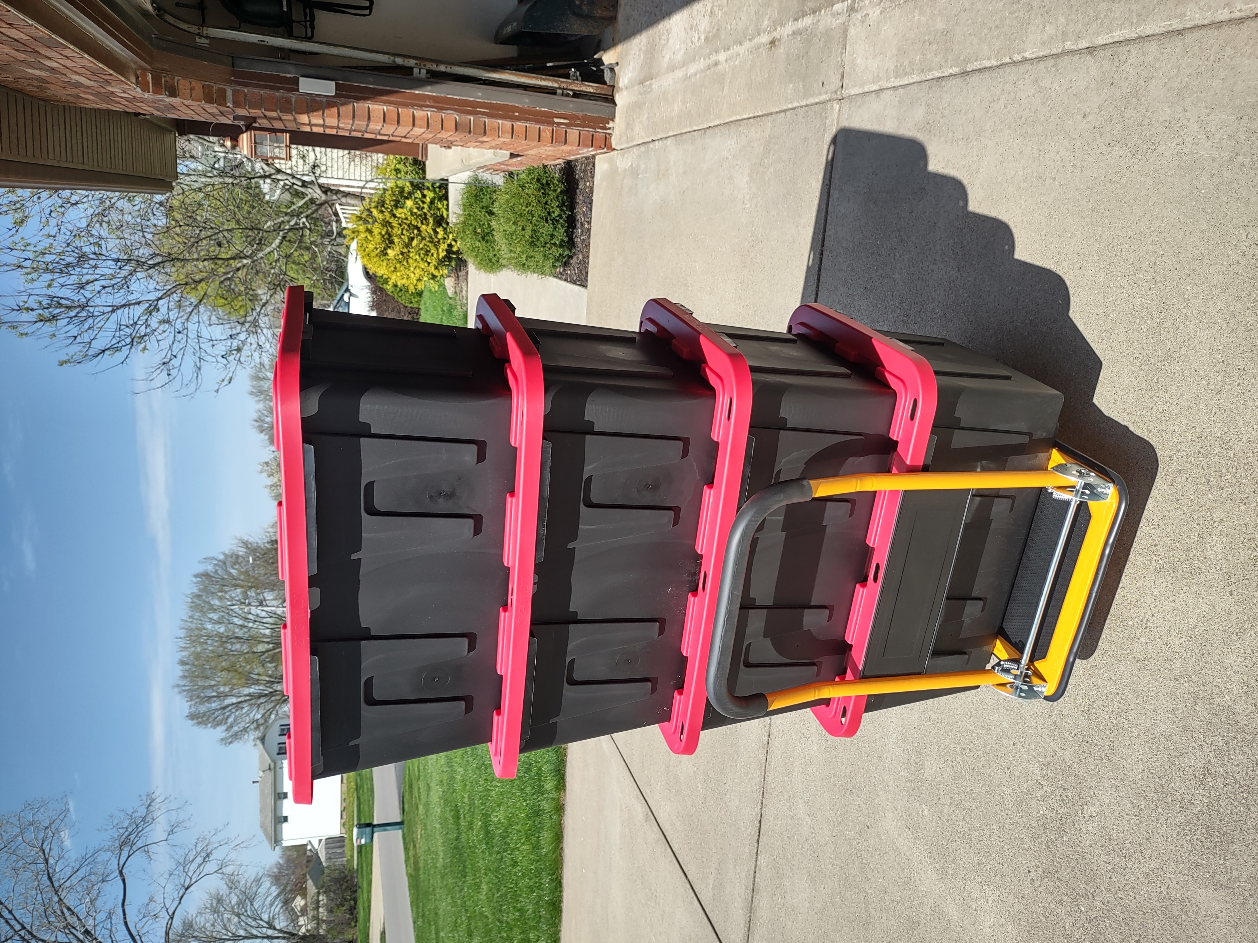 Stack of heavy-duty black and red reusable moving totes on a dolly