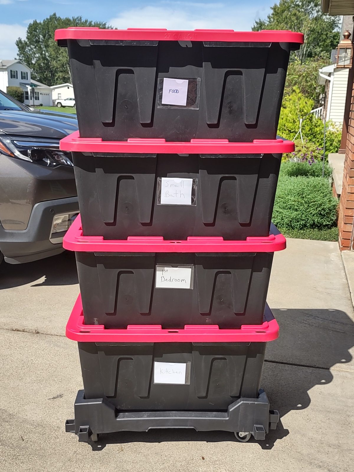 Stack of heavy-duty black and red reusable moving totes with room labels on Buffalo Tote Rental's flat dolly